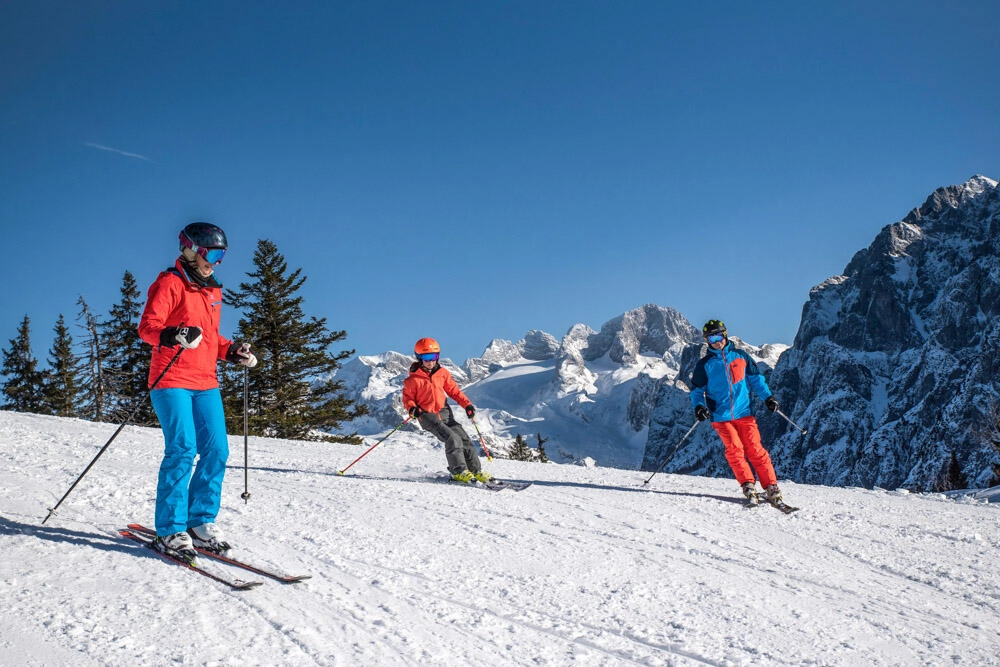 Eine Familie die eine Skipiste mit ihren Skier herunterfahren